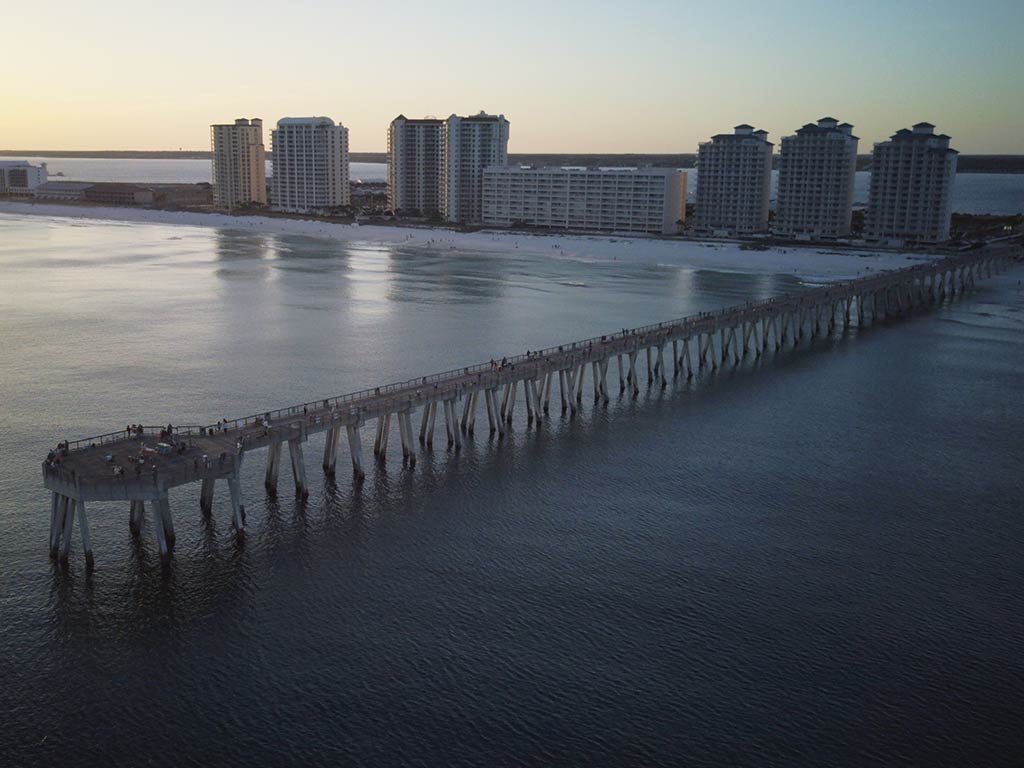 An aerial view looking towards the beach and town of Navarre, with the legendary fishing pier in the foreground sticking out into the water just after sunset