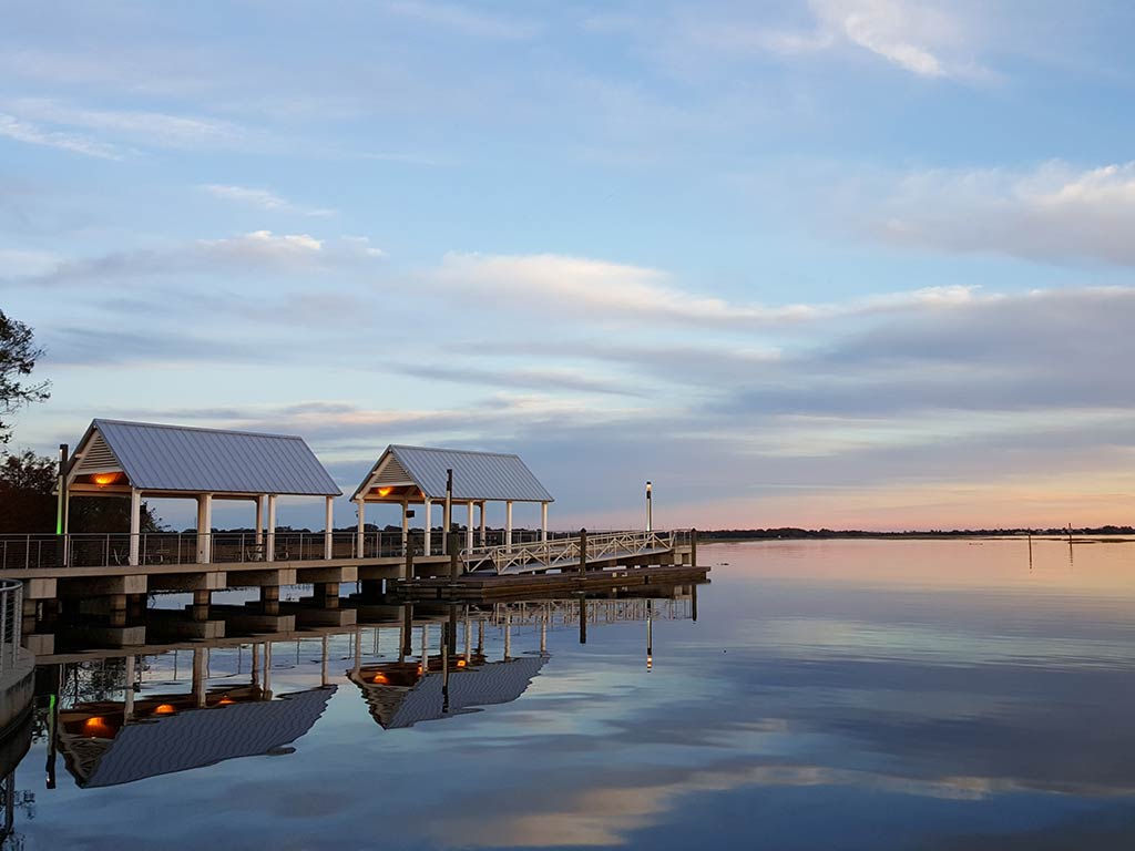 A view across the water towards a boat landing on Lake Kissimmee, FL, at sunset, with calm waters dominating the image