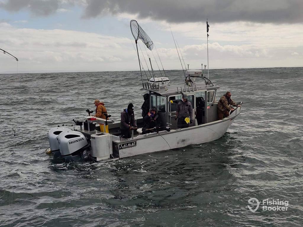 A fishing boat in the Puget Sound full of anglers casting into the water in pursuit of Salmon on a cloudy day with nothing around them but water