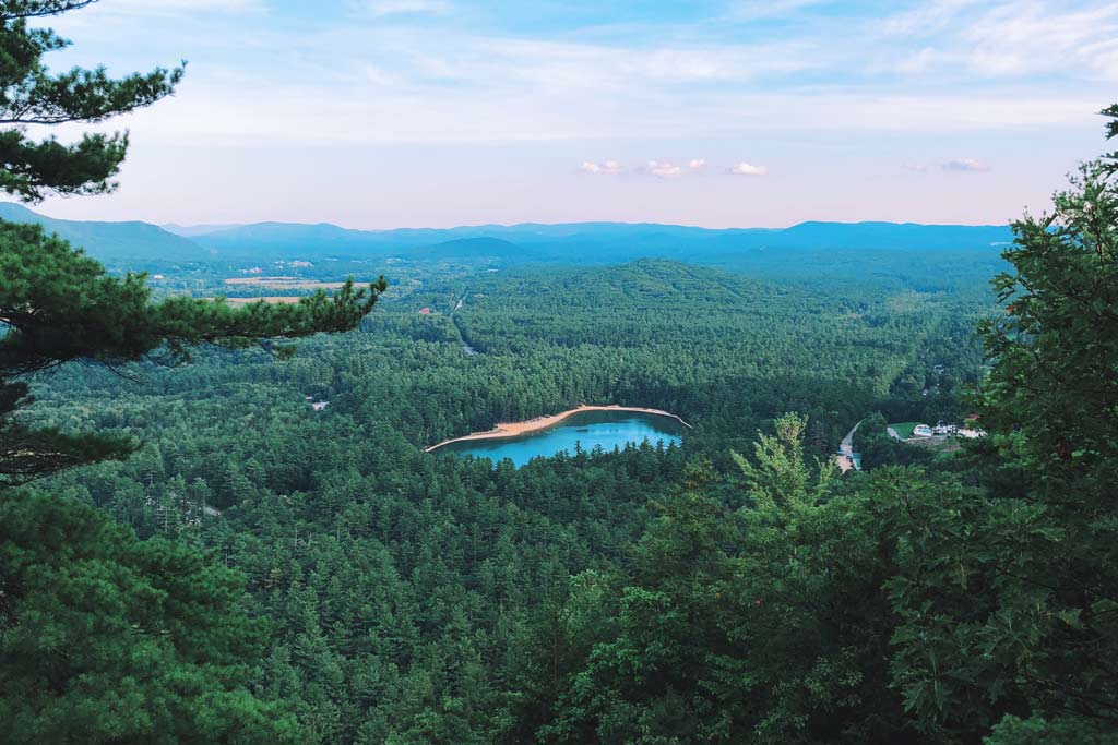 An aerial view of the strikingly blue Echo Lake near North Conway in Mount Washington Valley, with dense dark green forest surrounding the lake.