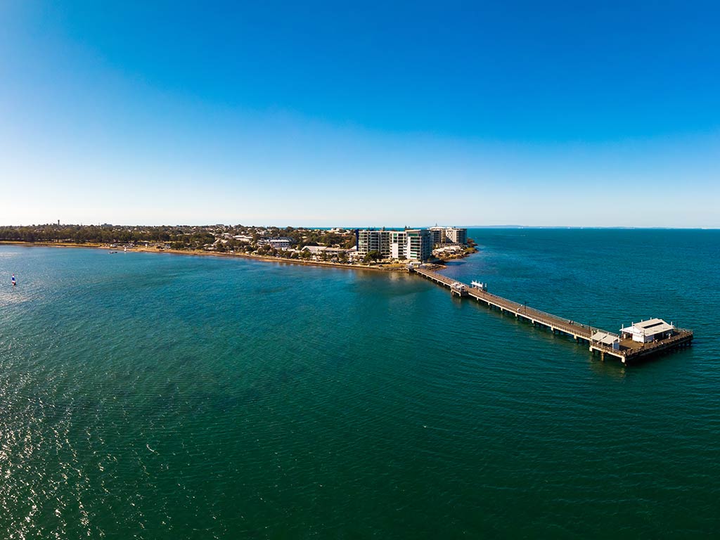 An aerial view across the water to Jetty Point and its fishing pier in Moreton Bay, Australia, on a sunny day