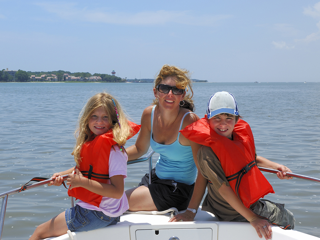 Mother and children wearing safety vests on a fishing boat.