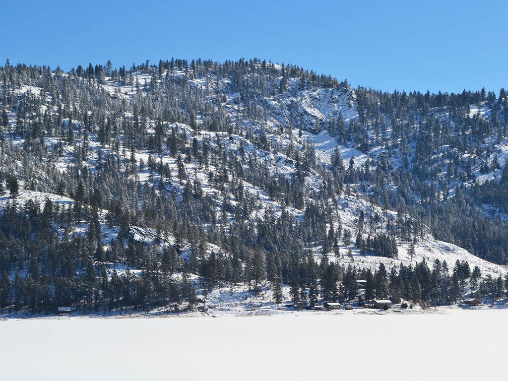 A view across a frozen lake towards a tree-covered mountain in Washington state on a clear day