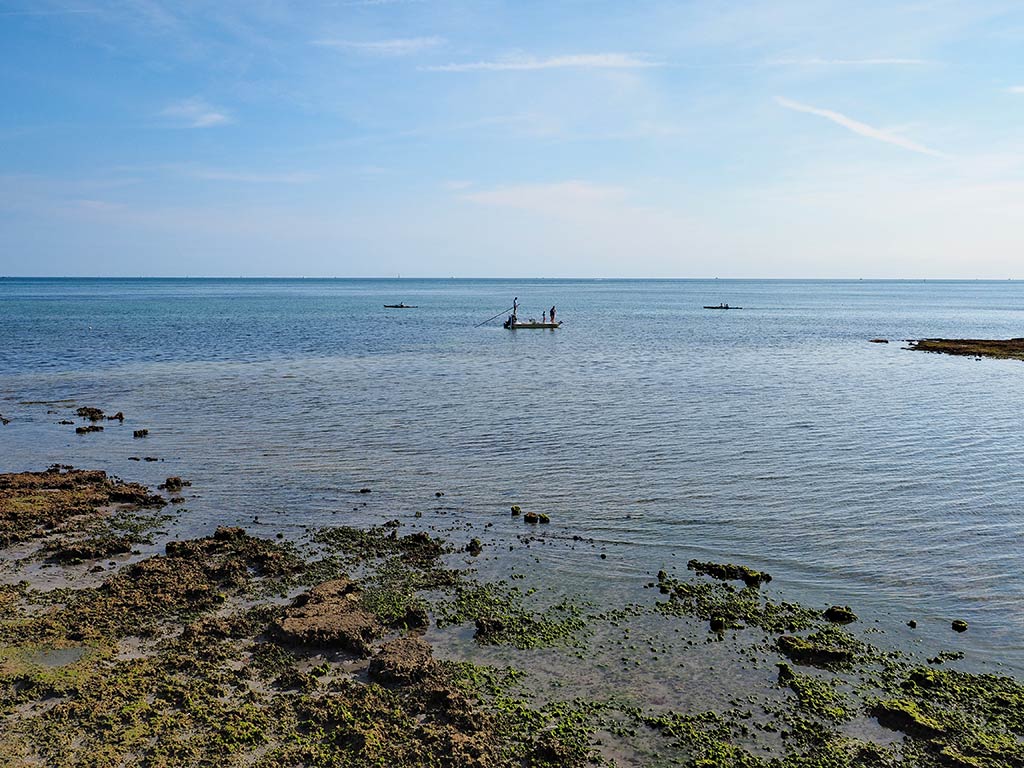 A view across the flats of Key Biscayne towards a lone fishing boat, potentially fishing for Flounder inshore on a sunny day