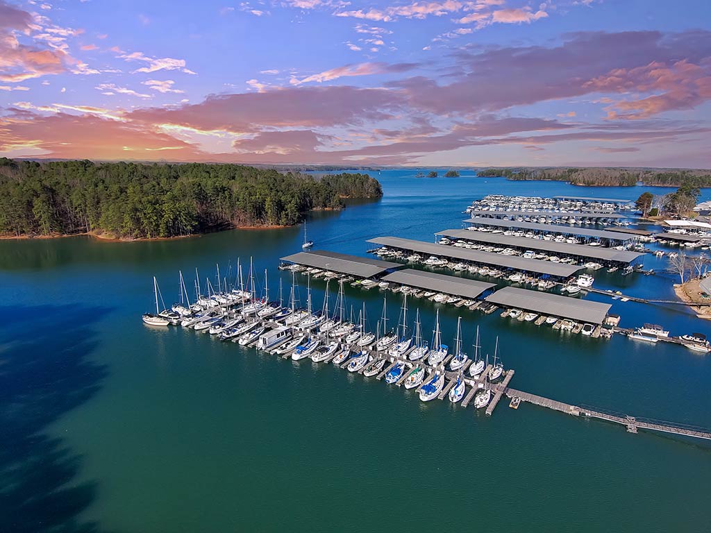 An aerial view of a marina in Lake Lanier, with a number of fishing boats docked at sunset on a day with sunny intervals