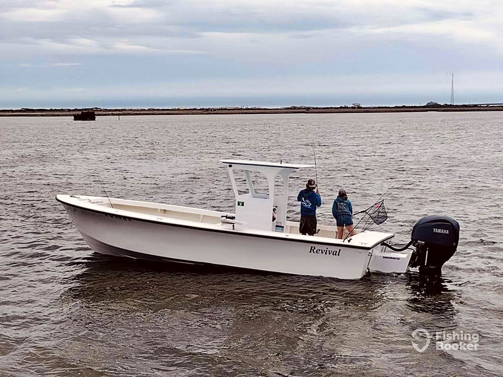 A small center console fishing boat drifts along the inshore sounds near Manteo, with two anglers fishing off the opposite side on a cloudy day