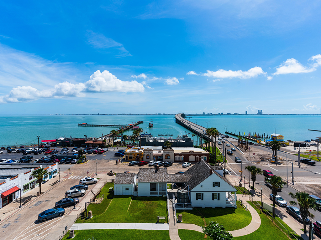 A view from above towards the Laguna Madre from Port Isabel, TX, on a sunny day, with the town visible in the foreground and the water in the distance along with a bridge