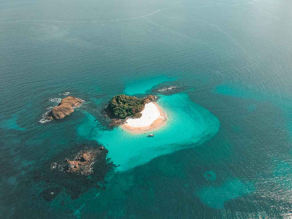 An aerial view of the Coiba Islands in Panamá, with three small islands and one white beach visible in turquoise waters