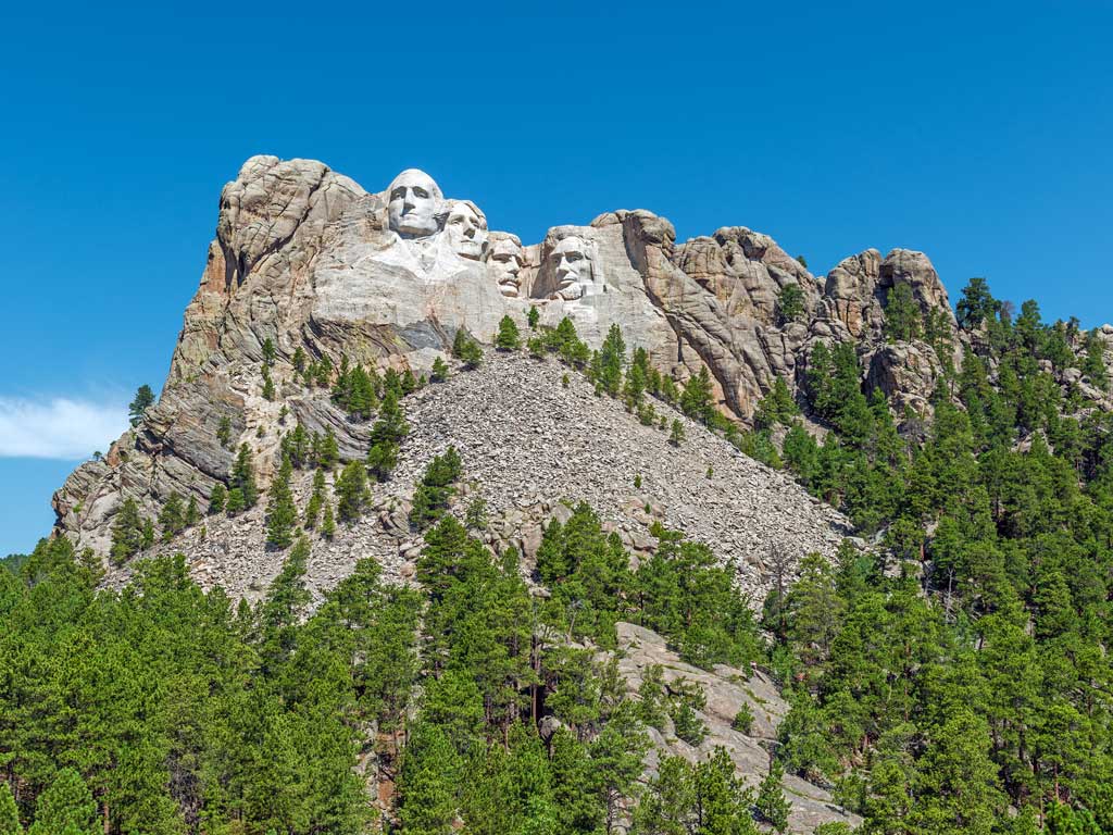 A view of Mount Rushmore as seen in the distance from below in Rapid City, South Dakota on a bright and sunny summer day