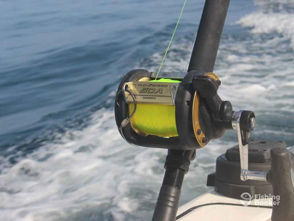 A closeup of a heavy-duty trolling reel on a fishing boat in Panamá, with the wake of the boat visible in the water behind it