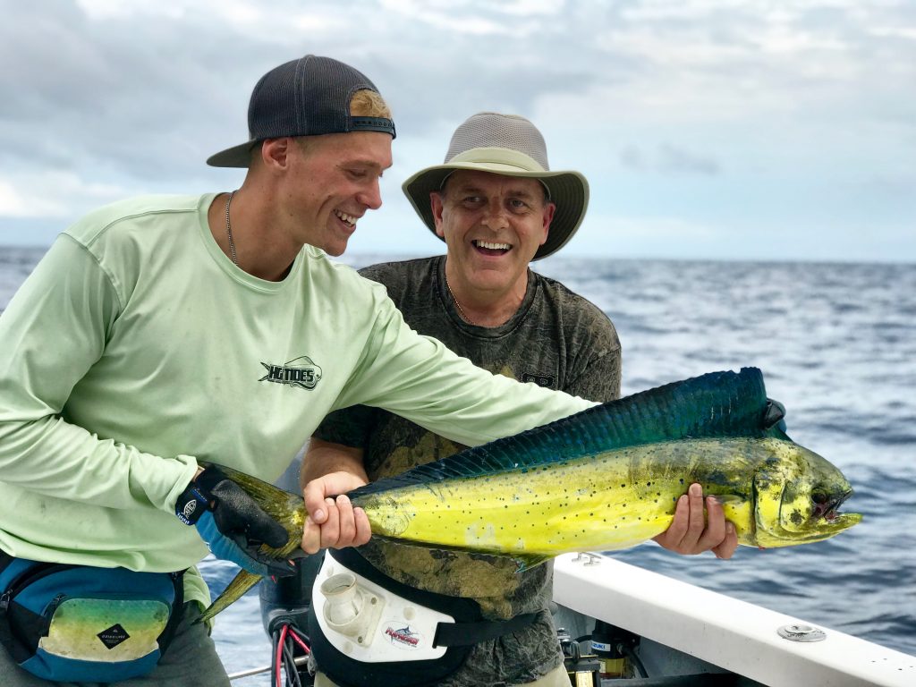 pescatori sorridenti in possesso di un Mahi Mahi su una barca da pesca