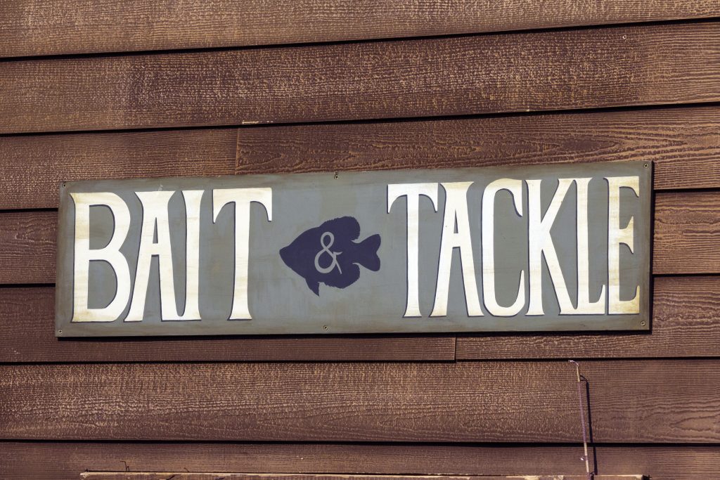 A sign on a wooden wall advertising a bait and tackle shop, a common place to buy a Michigan fishing license.