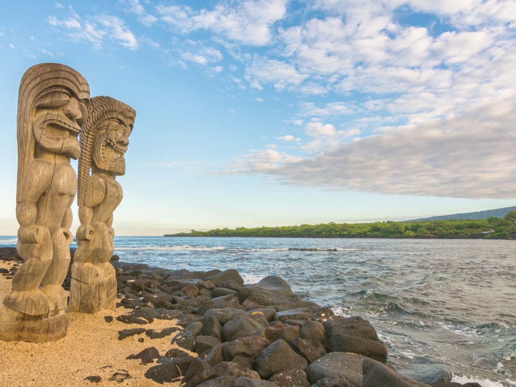 A view of the Big Island showing ancient statues in the foreground and the ocean in the background
