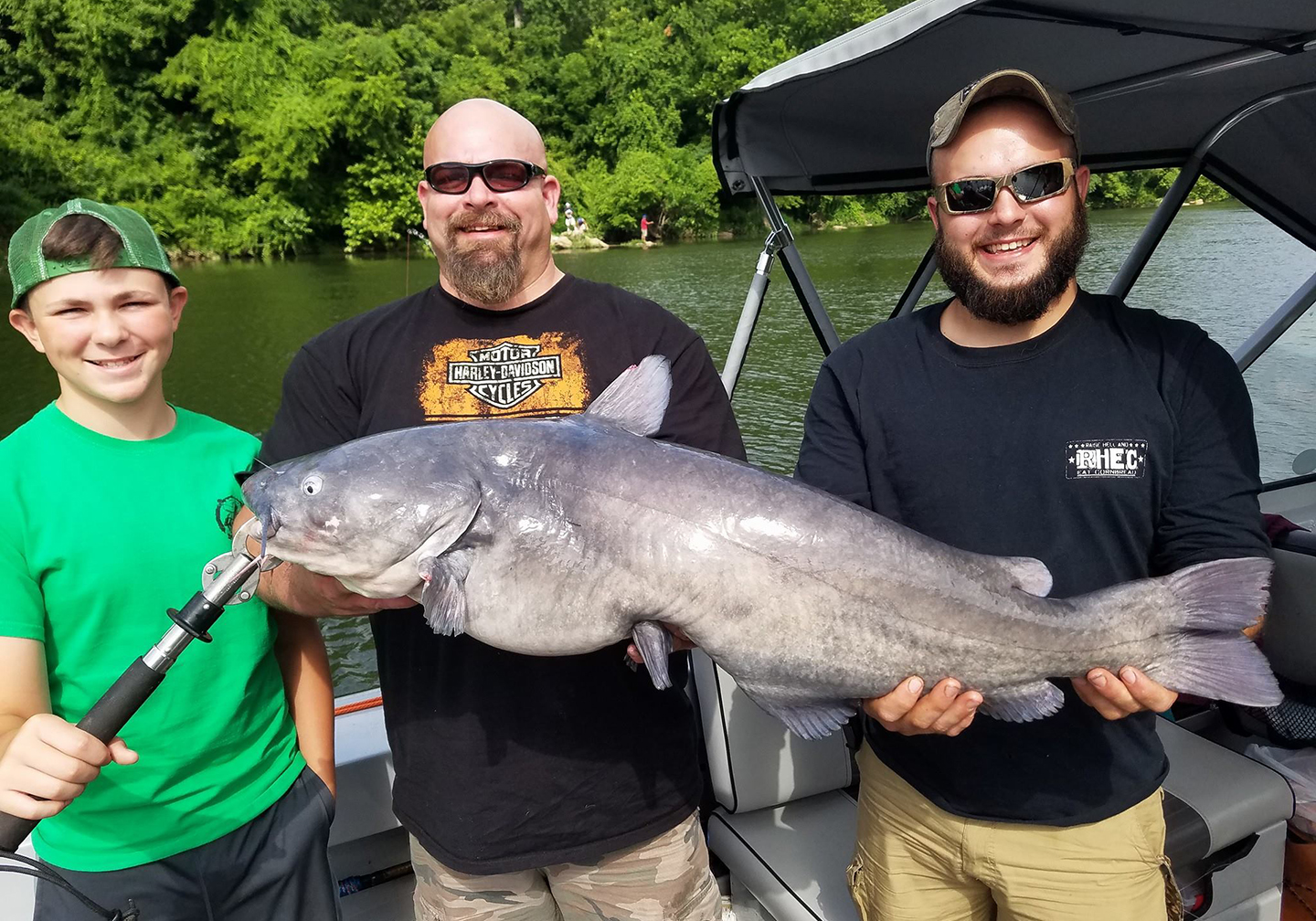 Three men holding a Blue Catfish after learning how to catch Catfish on a f...