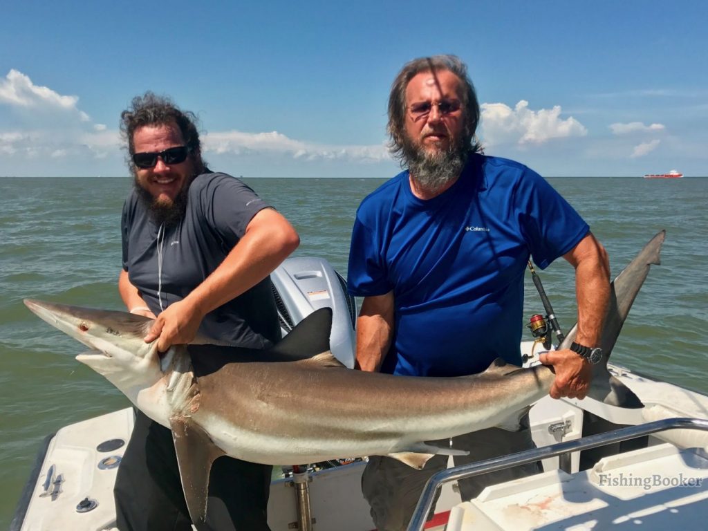 two anglers holding a Bull Shark they caught fishing the Texas coast