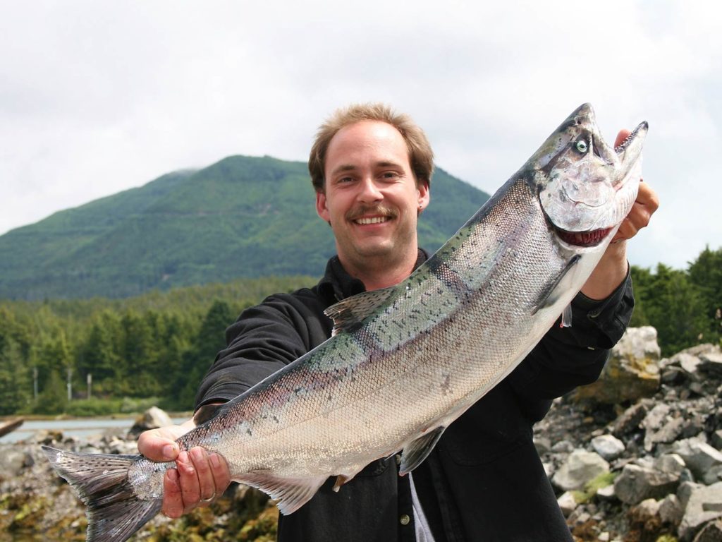 An angler holding a Chinook Salmon on a lake in Canada