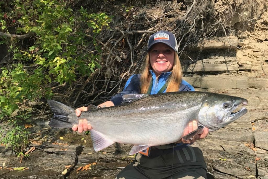 en leende fiskare som håller en stor Coho lax fångad i Lake Ontario bifloder.