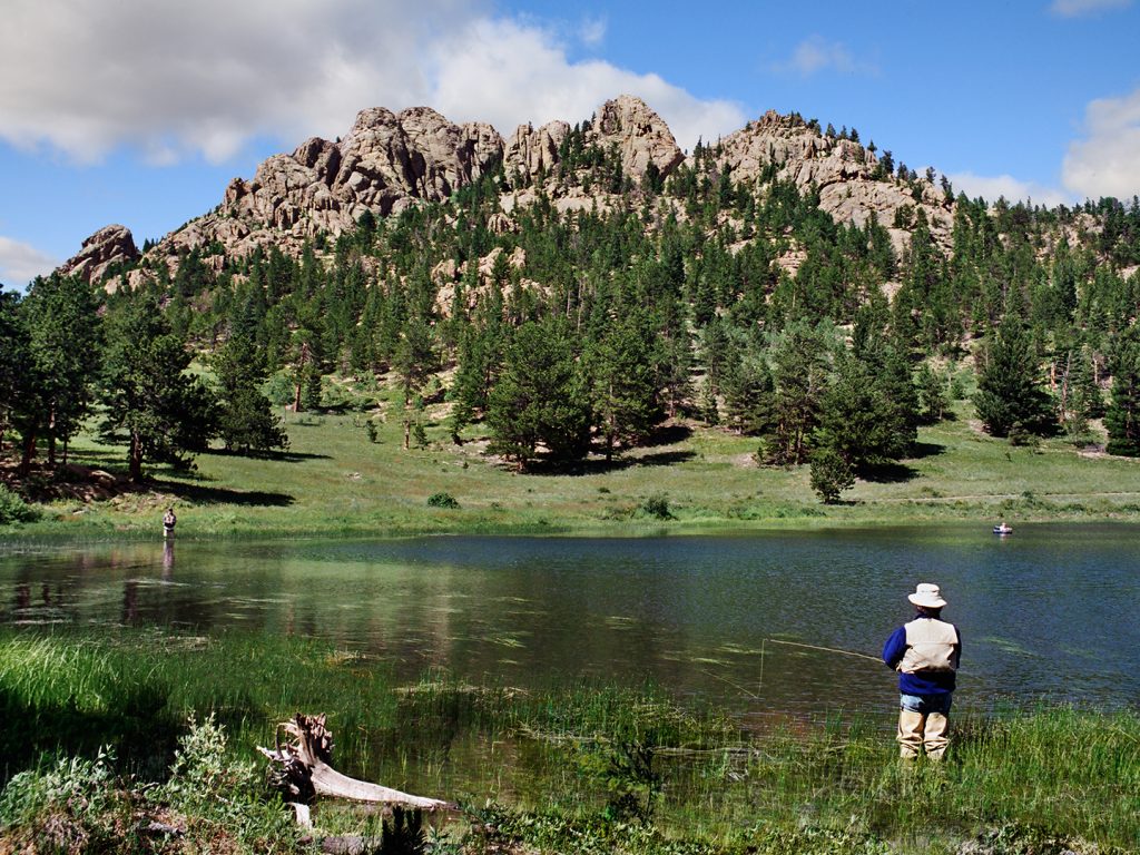 A man fishing in the Rocky Mountains while wading