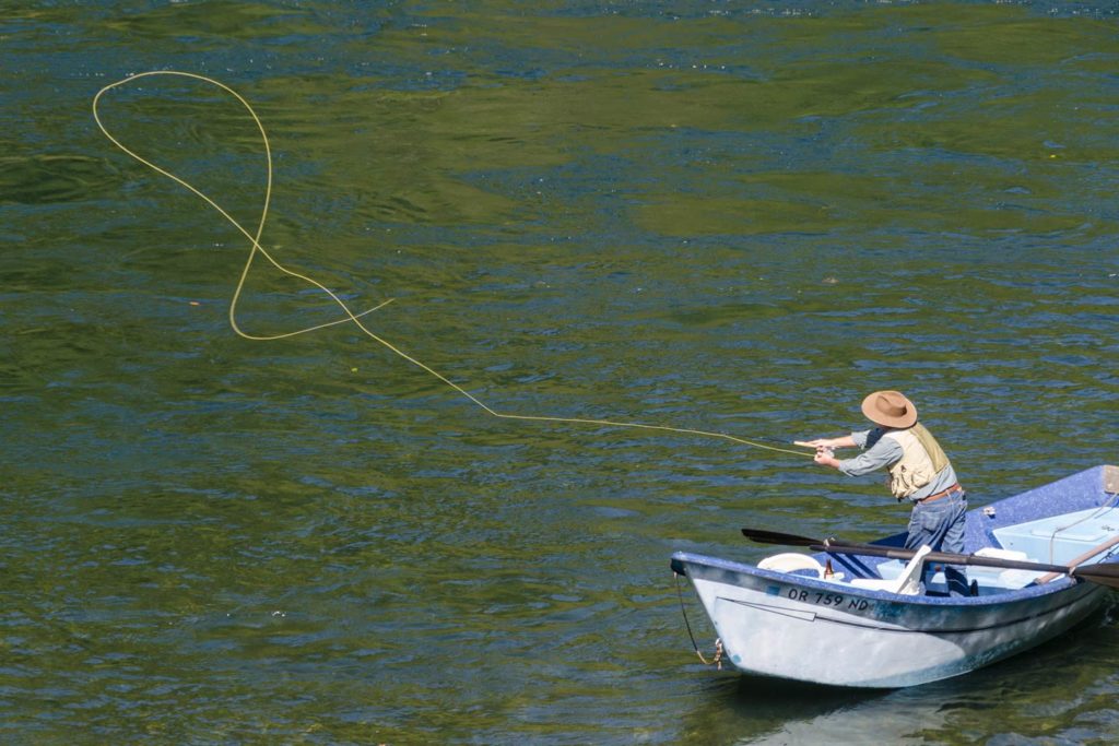 Ein Angler, der von einem Süßwasser-Treibfischerboot aus wirft.