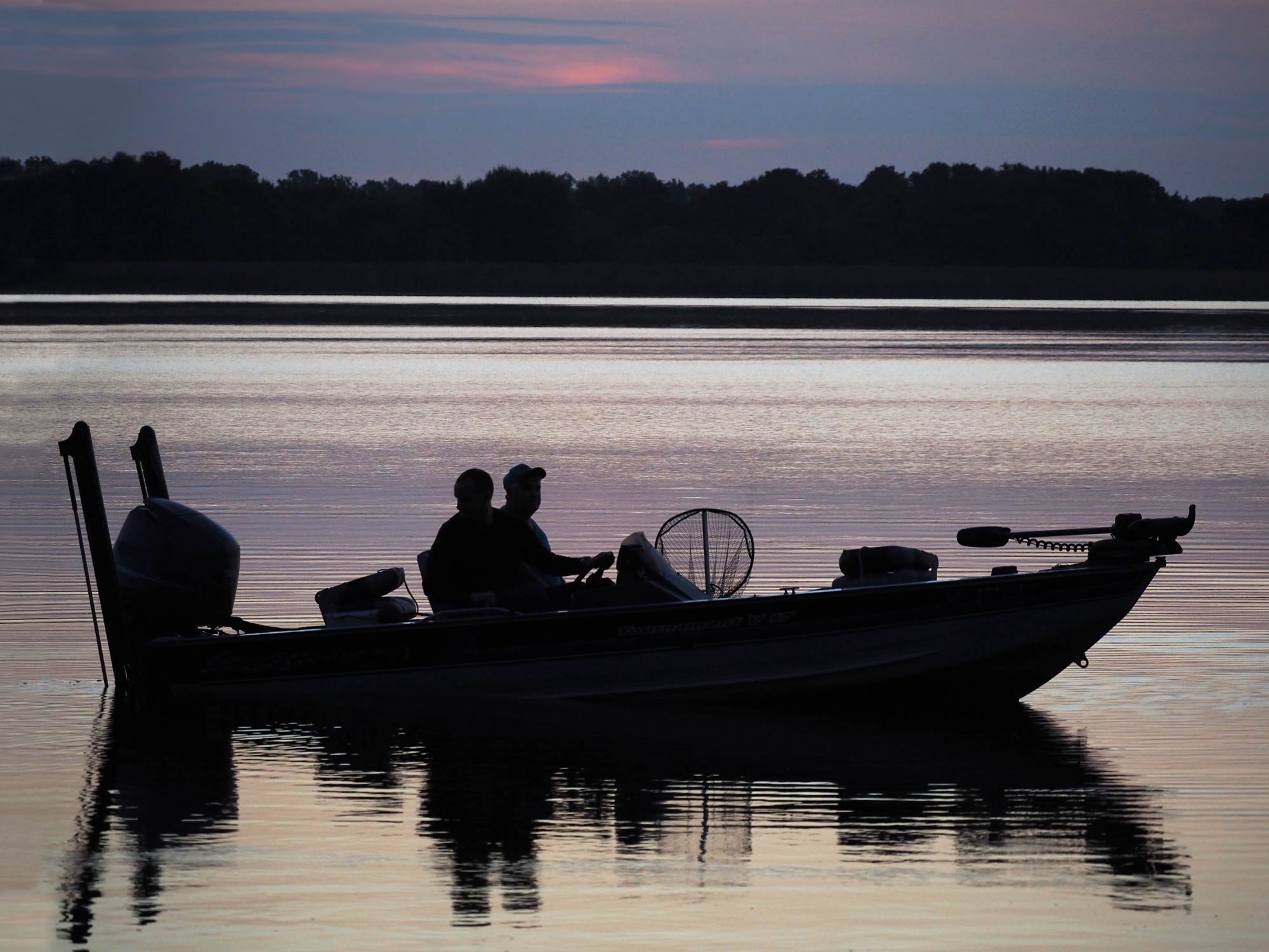 Un couple de pêcheurs à la ligne sur l'eau avant le lever du soleil