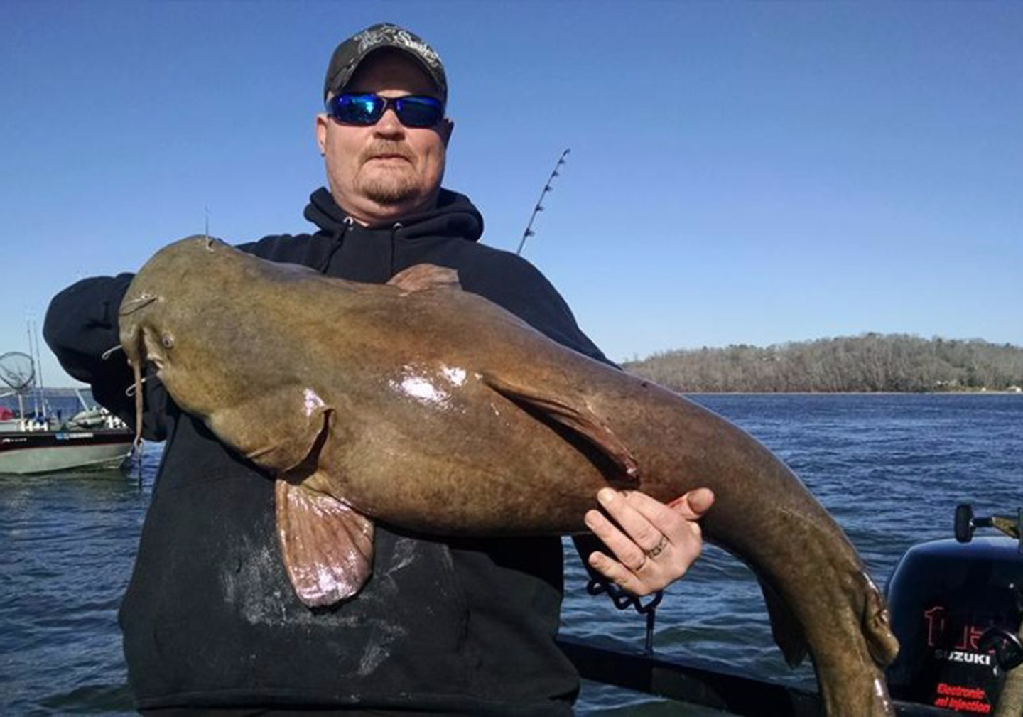 A man on a catfishing trip holding a large Flathead Catfish