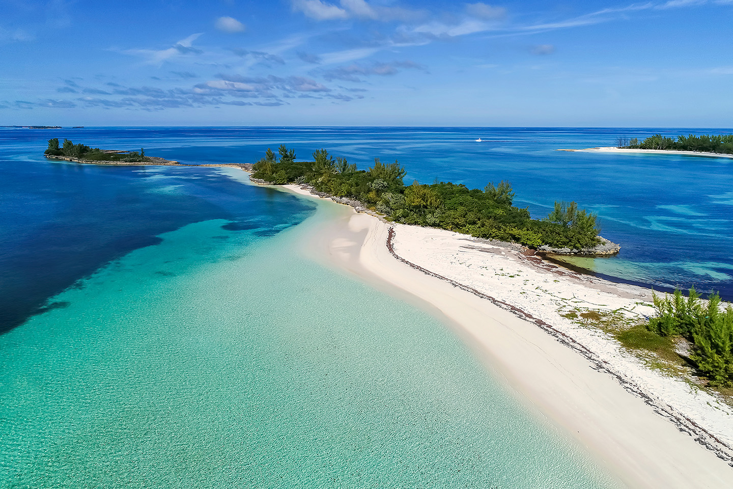 An aerial view of shallow flats and a thin island in the Bahamas