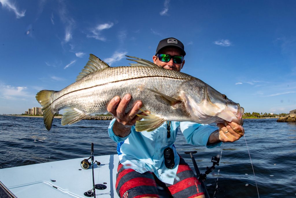 An angler holding a Snook on a boat in Fort Lauderdale