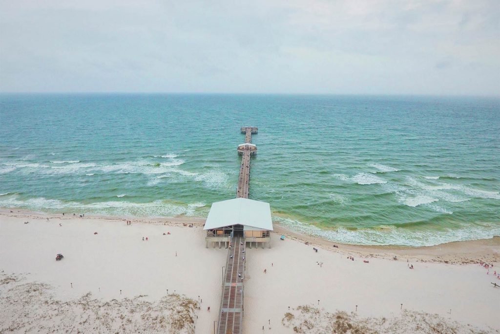 An aerial view of Gulf Shores fishing pier sticking out into the Gulf of Mexico while the waters are choppy