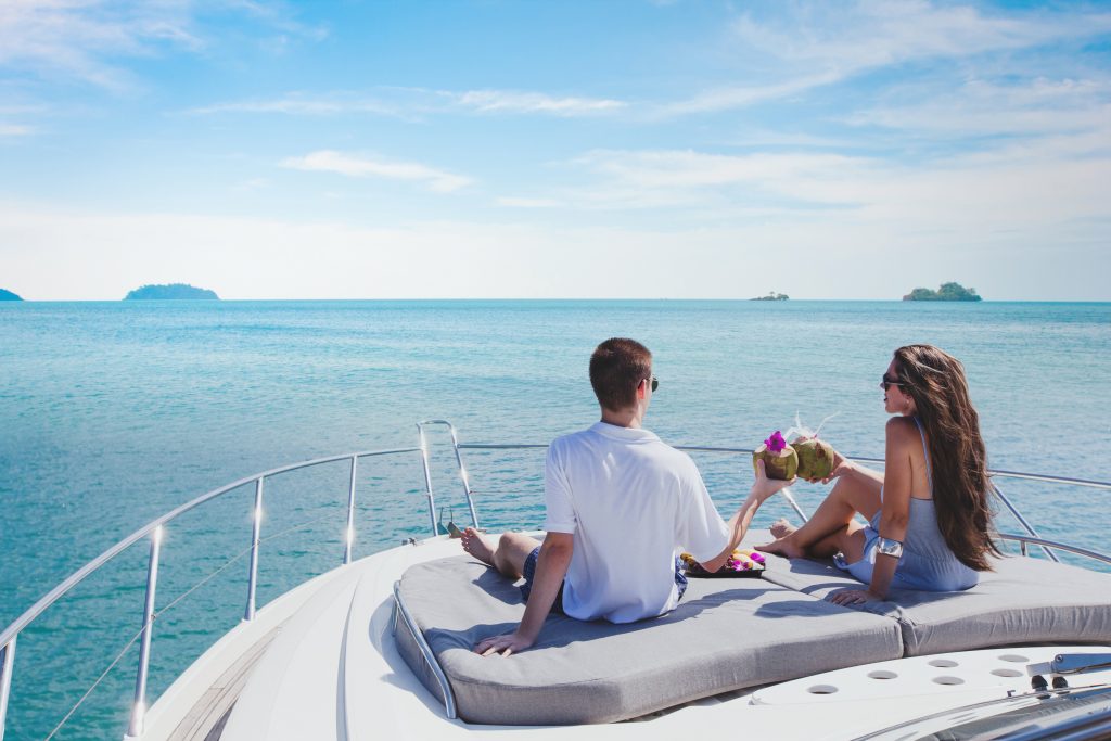 A happy couple toasting while sittnig at the front of a luxury charter boat at sea