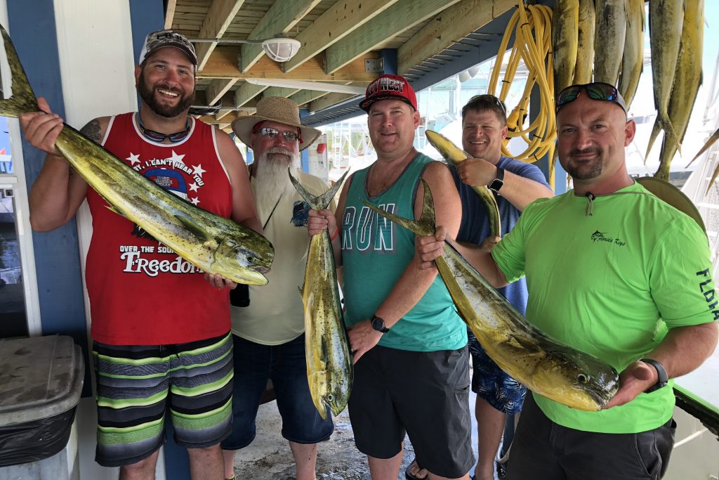 Un grupo de pescadores con pescado Mahi Mahi en el muelle después de un viaje de pesca