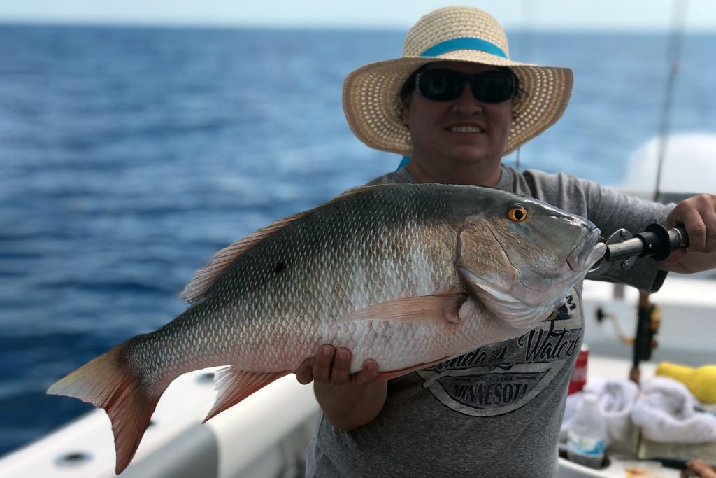 Una mujer sosteniendo un pargo de cordero grande en una carta de pesca de Islamorada