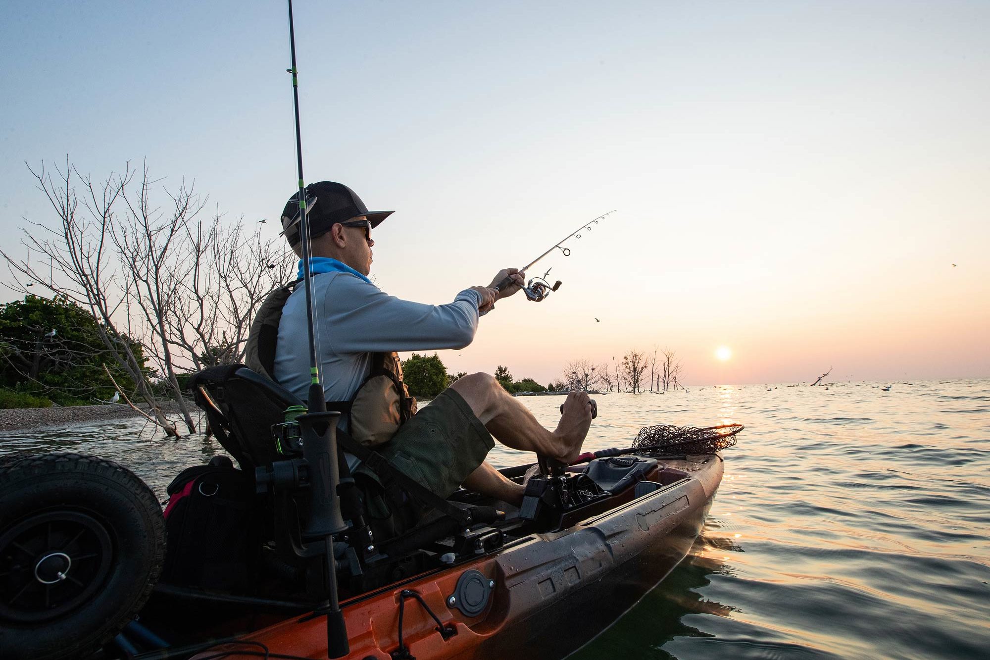 A kayak fisherman fishing from his kayak at sunset
