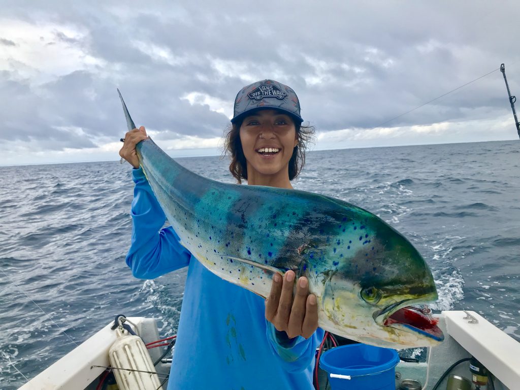 en smilende Kvindelig lystfisker, der holder en Mahi Mahi på en fiskerbåd