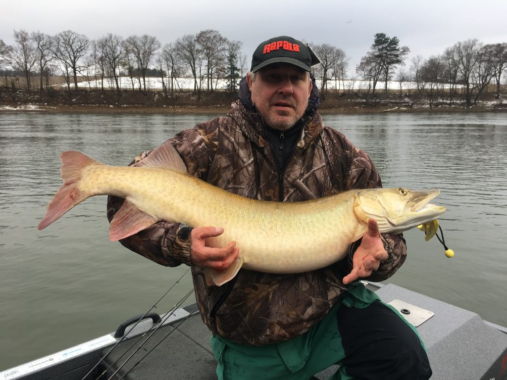 A proud fisherman holding a big Musky with the Susquehanna River in the background