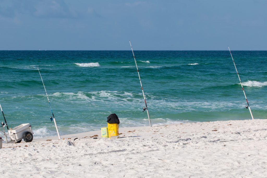 Une plage de sable blanc à Naples, en Floride. Il y a plusieurs cannes à pêche installées sur la plage pour la pêche du rivage