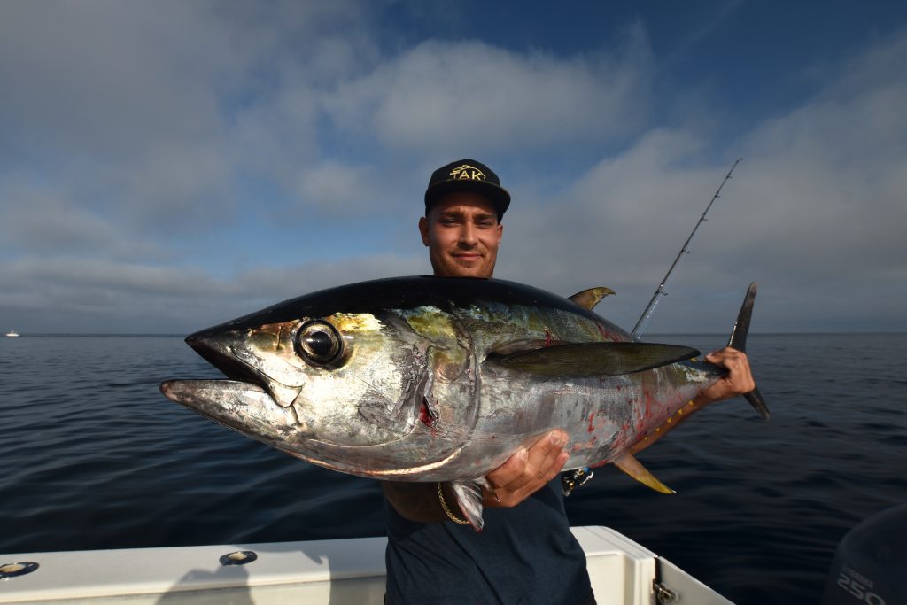 A man holding a large yellowfin tuna on a charter boat in the Gulf of Mexico