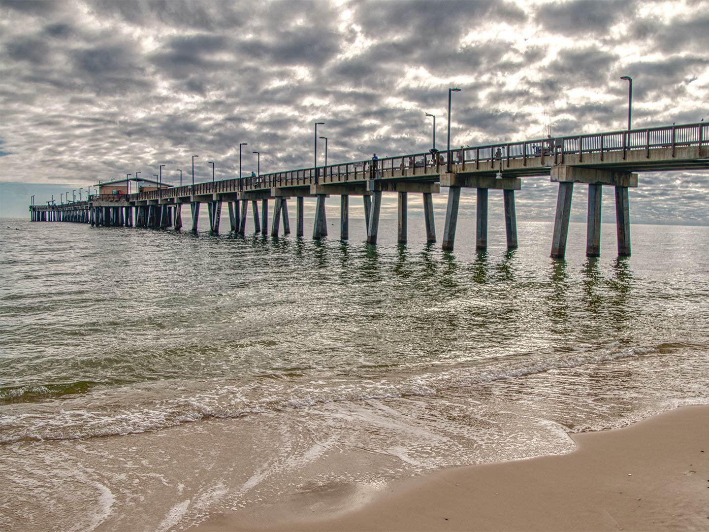 A view of the Gulf State Park Fishing Pier in Orange Beach from the beach on a cloudy day