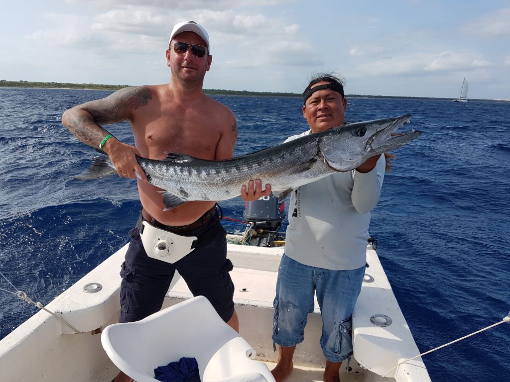 smiling anglers holding a Wahoo on a fishing boat in Playa del Carmen