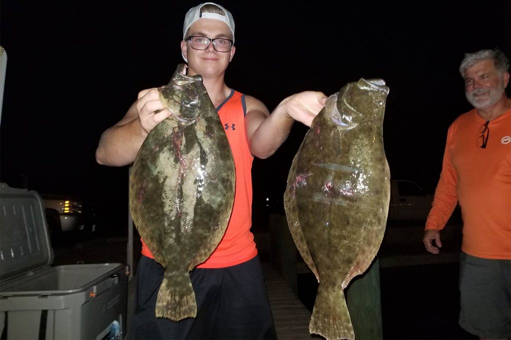 A young man holding two Flounders caught while night fishing in Port Aransas