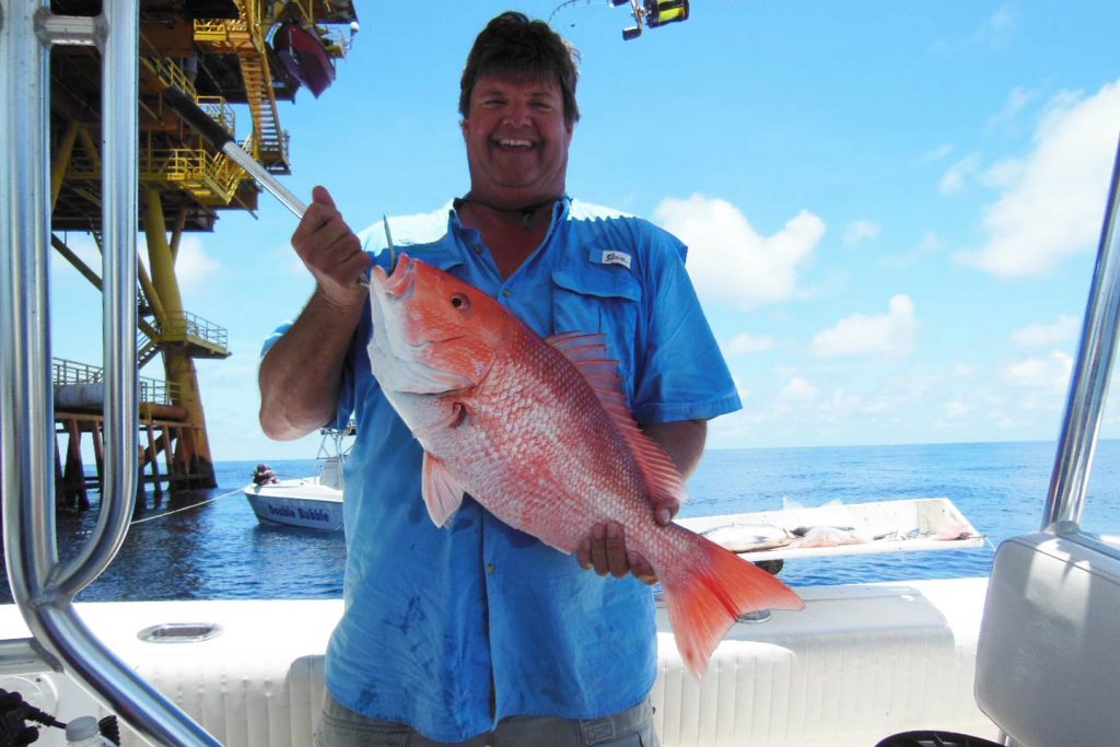 A man holding a Red Snapper caught while fishing the oil rigs of the Gulf of Mexico