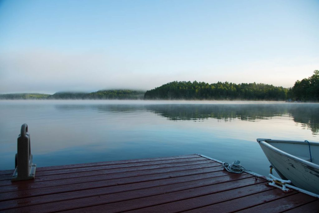 lakeside dock a rybářská loď na mlhavé ráno.