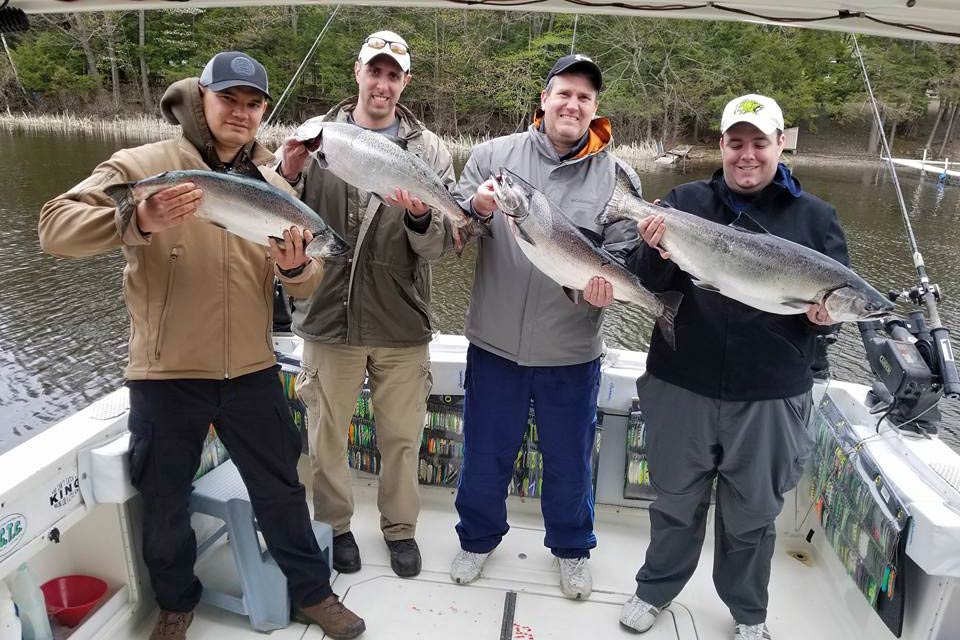 Eine Gruppe von Anglern, die am Ontariosee gefangenen großen Lachs halten