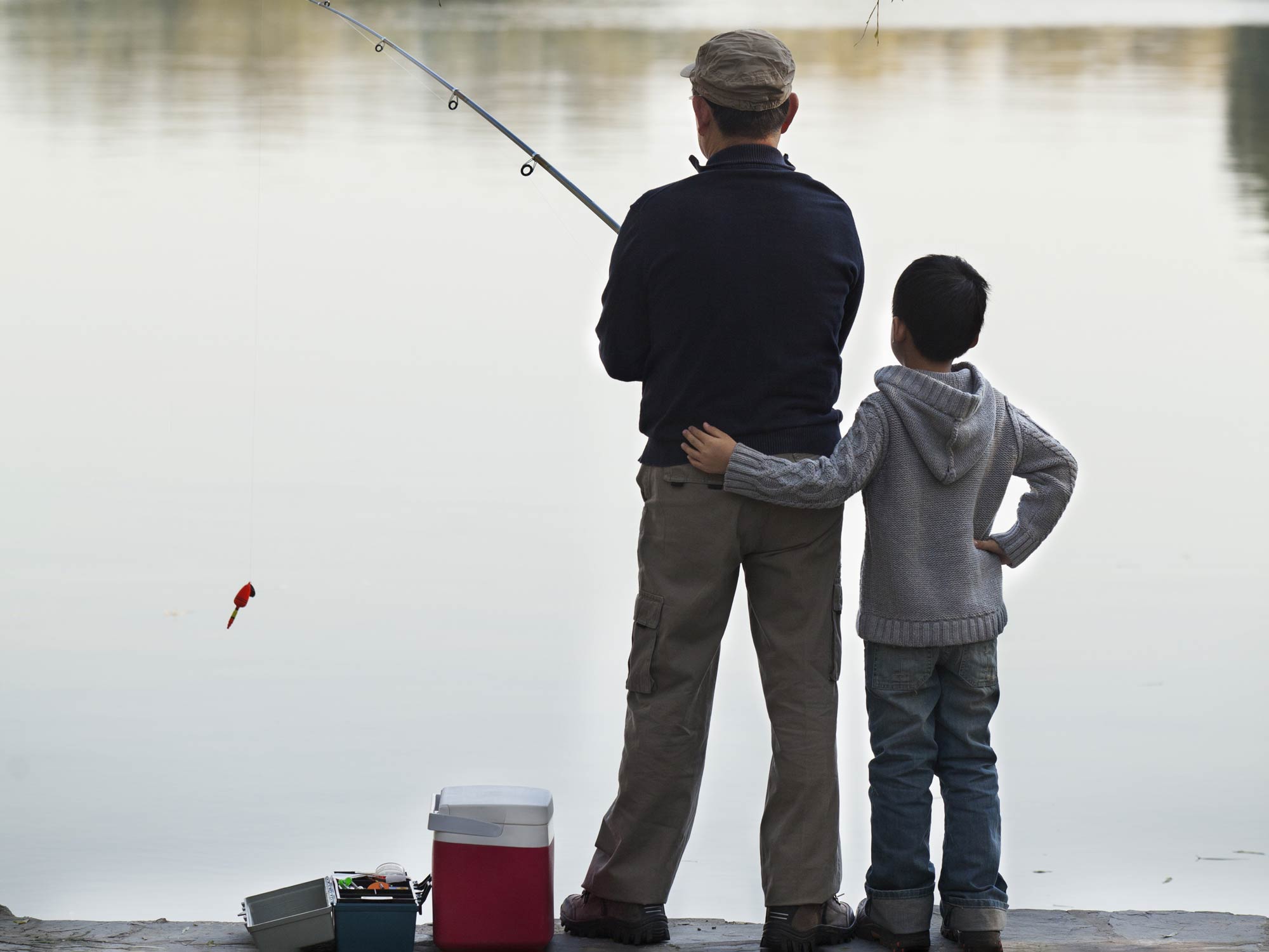 Muž a chlapec společně loví ryby ze břehu