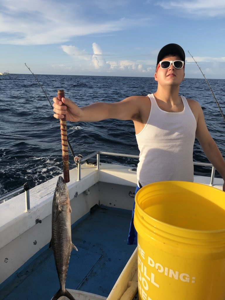 an angler posing with his fish on a fishing charter,showing that fishing is a great guilt-free activity to enjoy during the covid pandemic