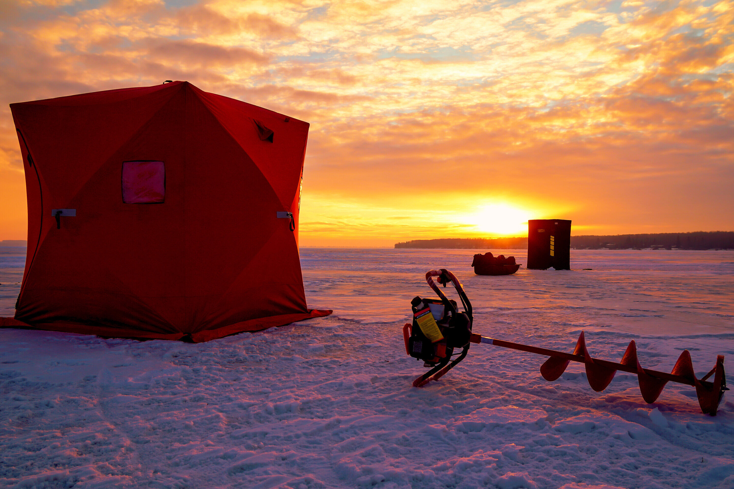 A tent and an ice drill on a frozen lake