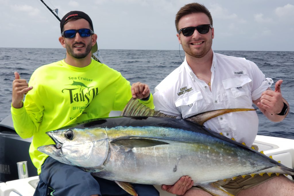 Two happy anglers posing on a boat with a large Yellowfin Tuna they just caught