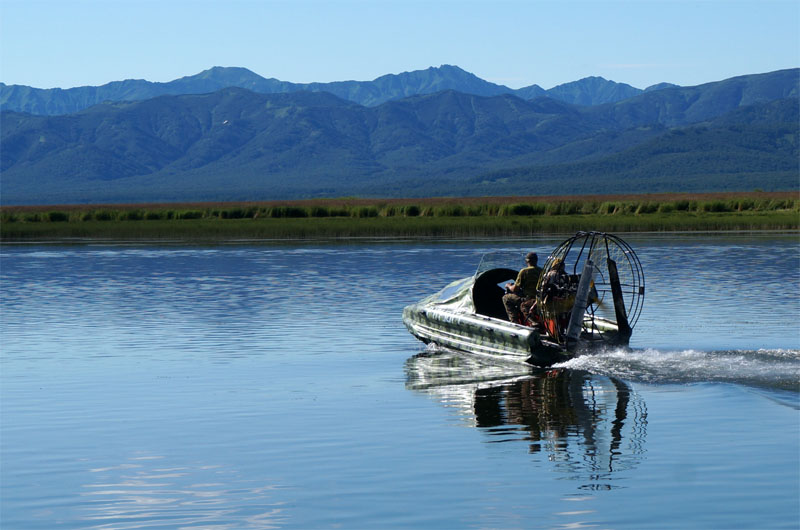 A view of a lonely boat on calm water with mountains in the background