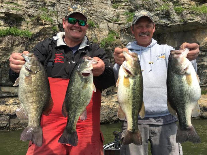 Two smiling fishermen holding up smallmouth bass and largemouth bass