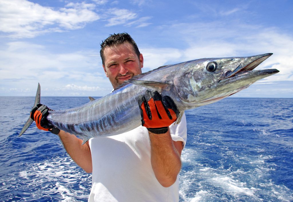 a satisfied angler holding a wahoo