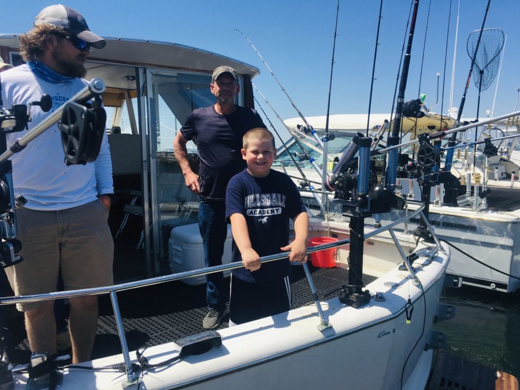 smiling anglers and a boy standing on a docked fishing boat